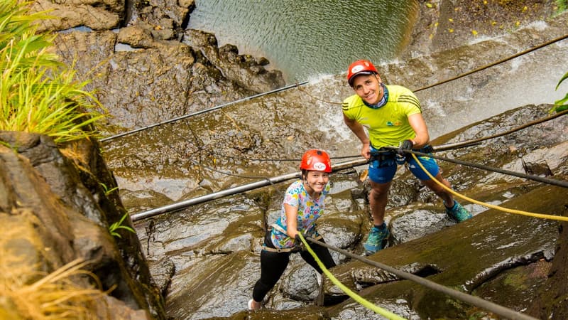 Dos personas con casco y arnés en las cuerdas junto a la cascada de Juan Curí.