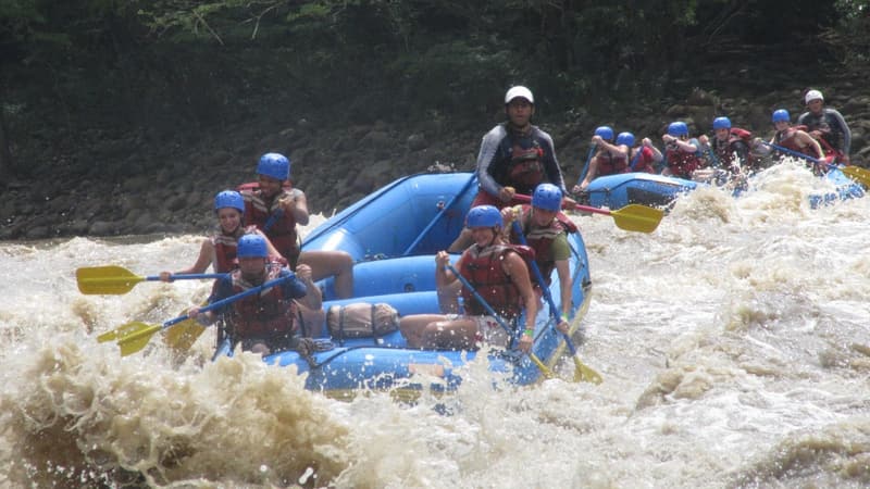 A raft punching through big white rapids with a second raft behind.